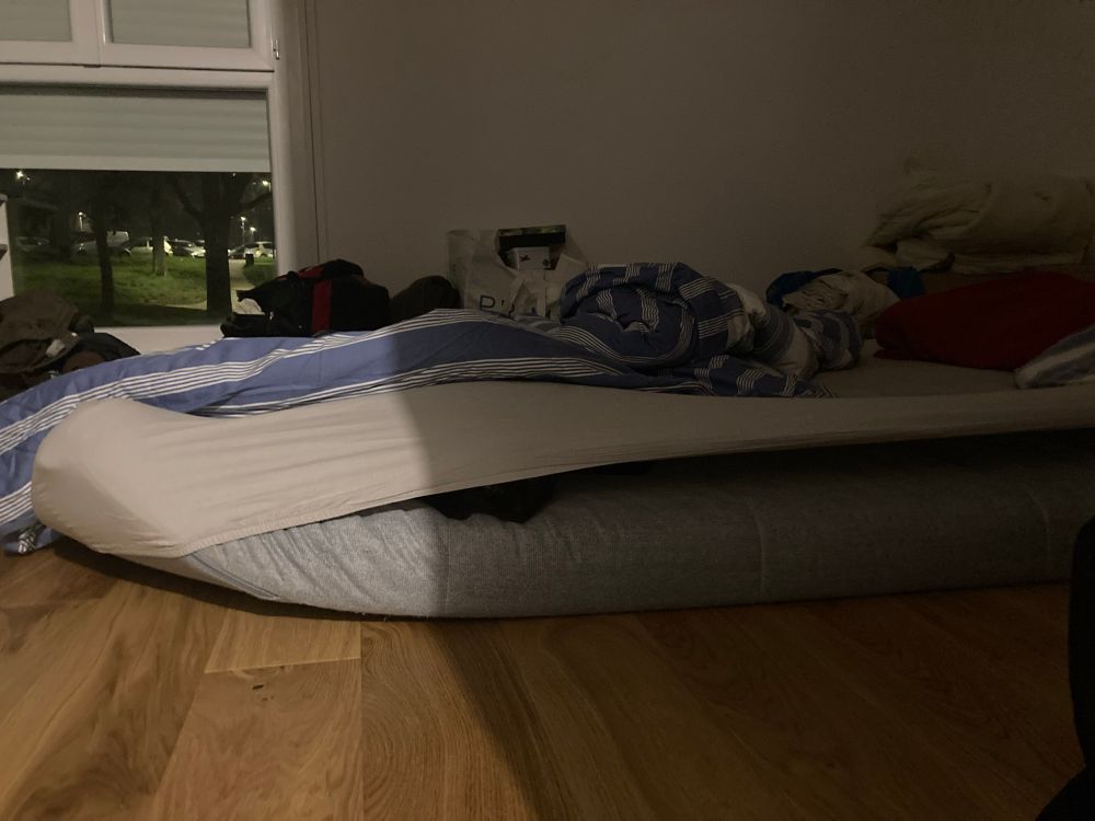 Matelas au sol avec le plus beau chat noir du monde entre le matelas et la housse par-dessus