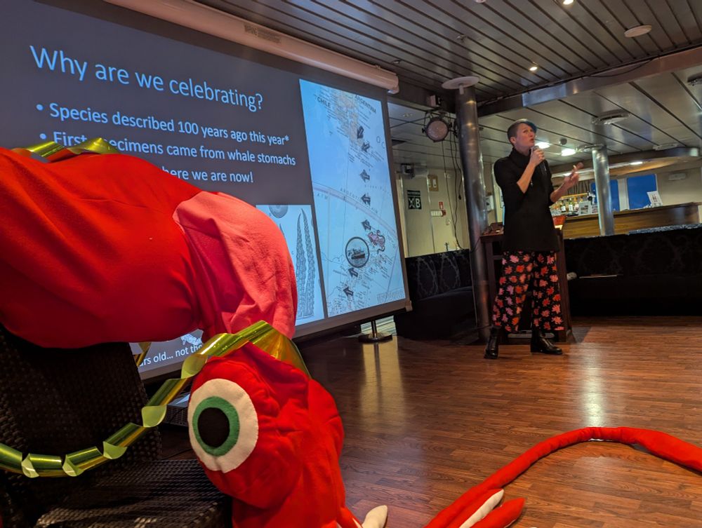 Kat Bolstad gives a lecture in the lounge aboard the Ocean Endeavour. A life-sized plush colossal squid joins her on stage.