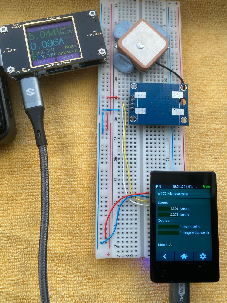 A touchscreen module on an electronics beadboard attached to a GPS module.  The screen displays a message from the module giving its speed and course, which apparently is 1.229 knots or 2.275 km/h for the stationery items.