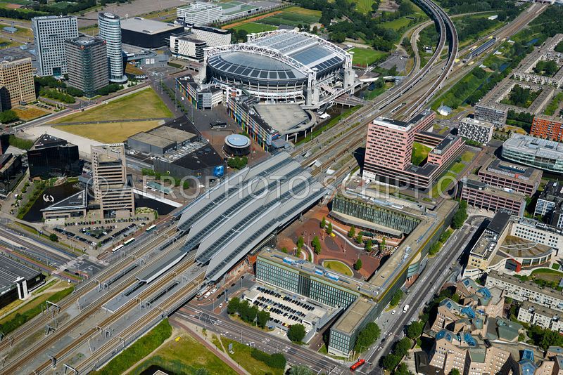 Drone shot of Johan Cruijff ArenA stadium in Amsterdam, the Netherlands, surrounded by buildings and in the neighbourhood of a large train station