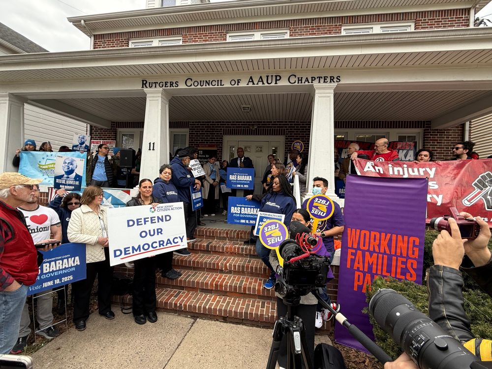 Ras Baraka speaking on steps of house surrounded by union members and various signs