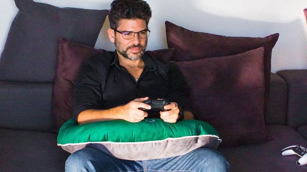 some dude using a "gamer pillow" on a couch