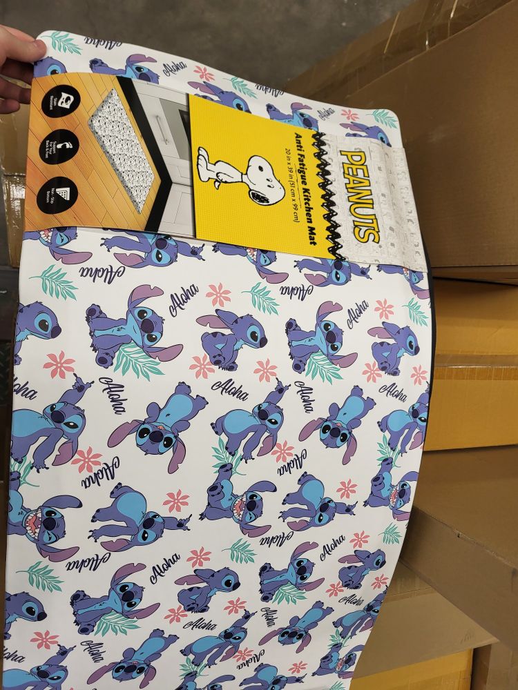 A picture of a stitch themed anti fatigue mat, with the packaging for a Peanuts themed anti fatigue mat instead