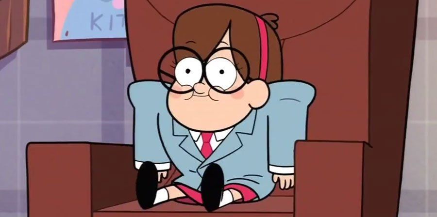 Mable, from gravity falls,is in a light gray, business suit. She is wearing black, rimmed, and round glasses. She is sitting in a brown, square chair and smiling big.