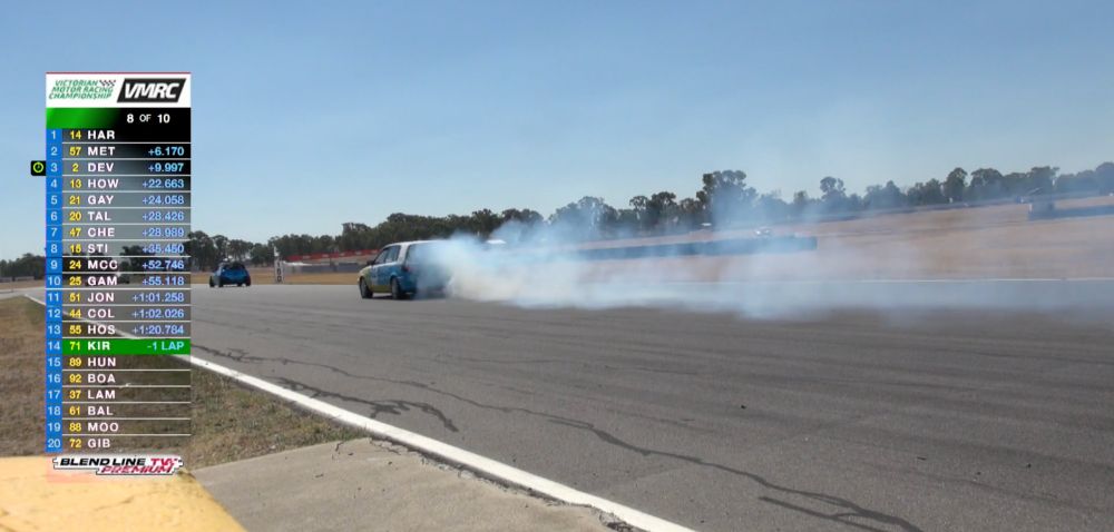 Toyota corolla race car driving to the left with a cloud of smoke trailing