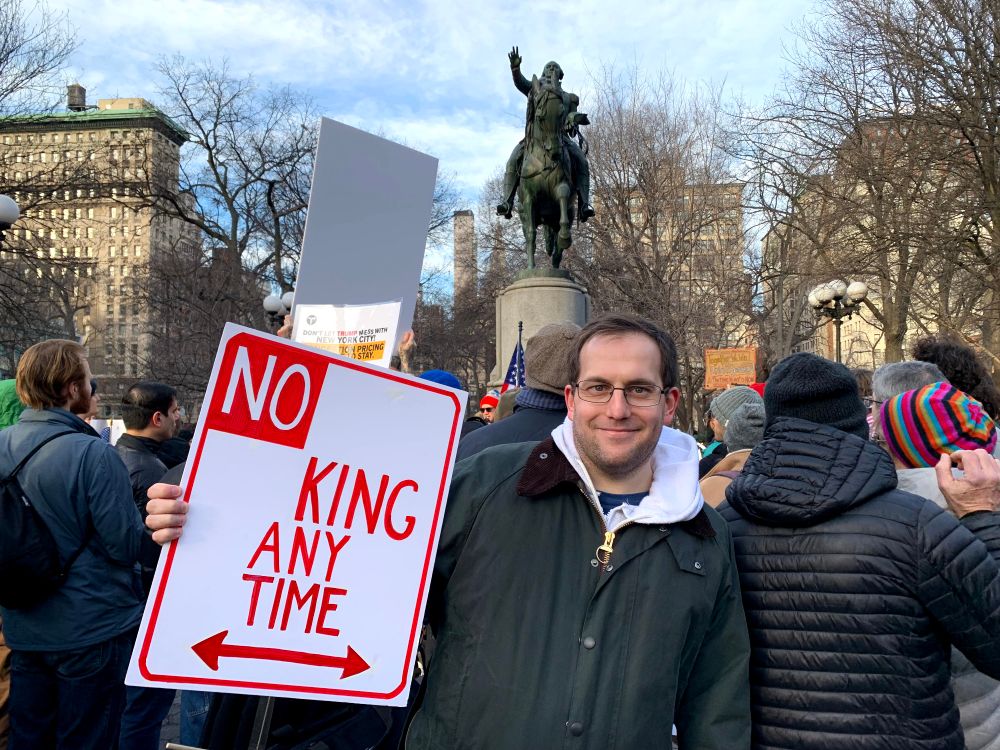 Ben Wetzler at an anti-Trump protest holding a "No King Any Time" sign in front of a statue of George Washington