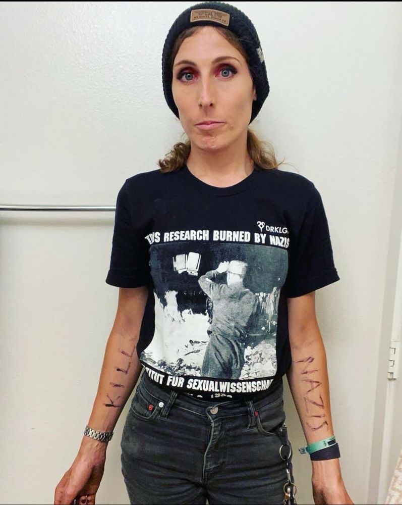 Trans Olympian Chelsea Wolf in our transphobia is Nazism shirt. The front is shown which has the trans research burning of 1933. 