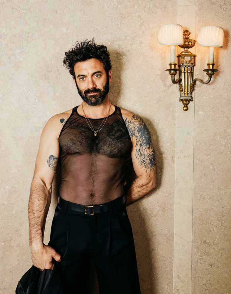 Morgan Spector wearing a slutty mesh top in a hotel hallway. 