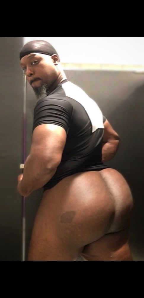 A bearded black man with a huge ass, showing off his cheeks in the stall of a public restroom 