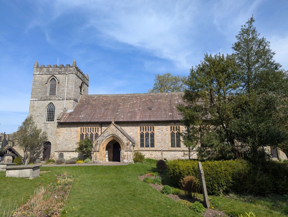 Exterior photo of kettlewell church on sunny day - tower is on left and nave and chancel on right. 