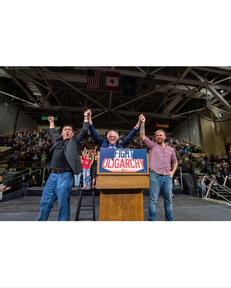 Troy Jackson, Bernie Sanders, Graham Platner with arms raised in unity. 