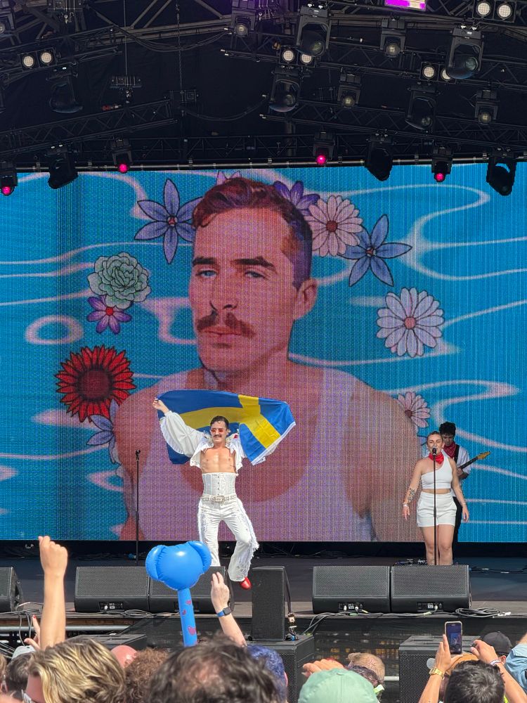 Pop Superstar Tom Aspaul wearing all white, performing a banger holding a Swedish flag 