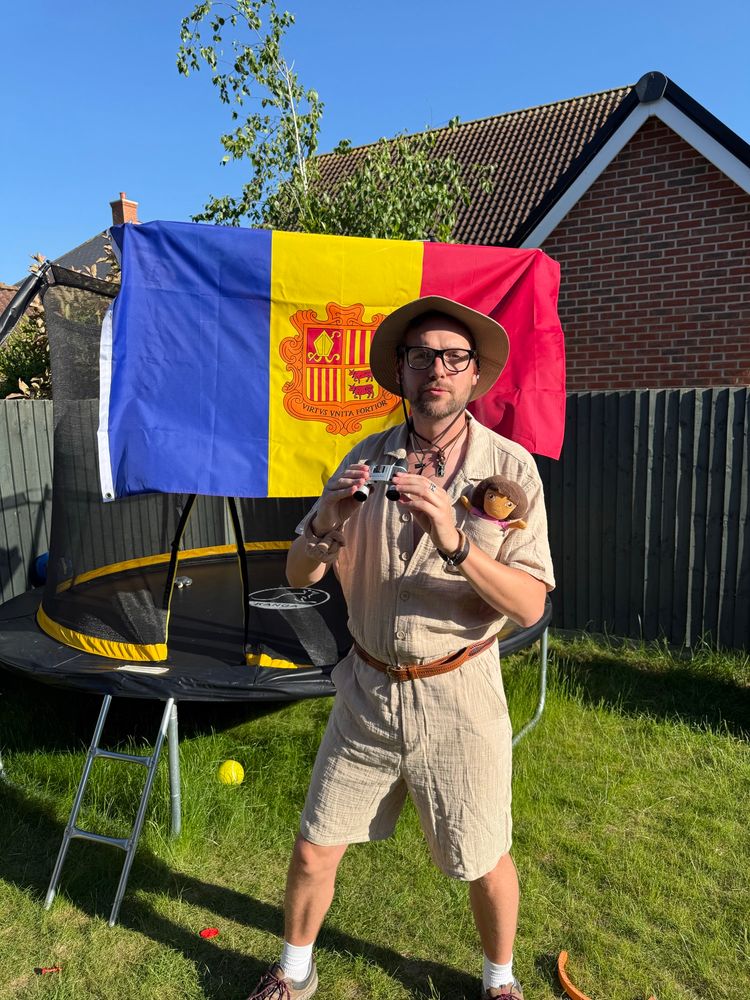 Matt dressed as an Explorer in front of an Andorran flag. 