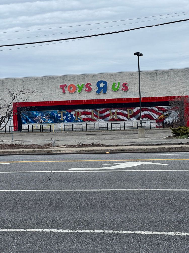 An abandoned toys r us with an American flag and Trump mural 
