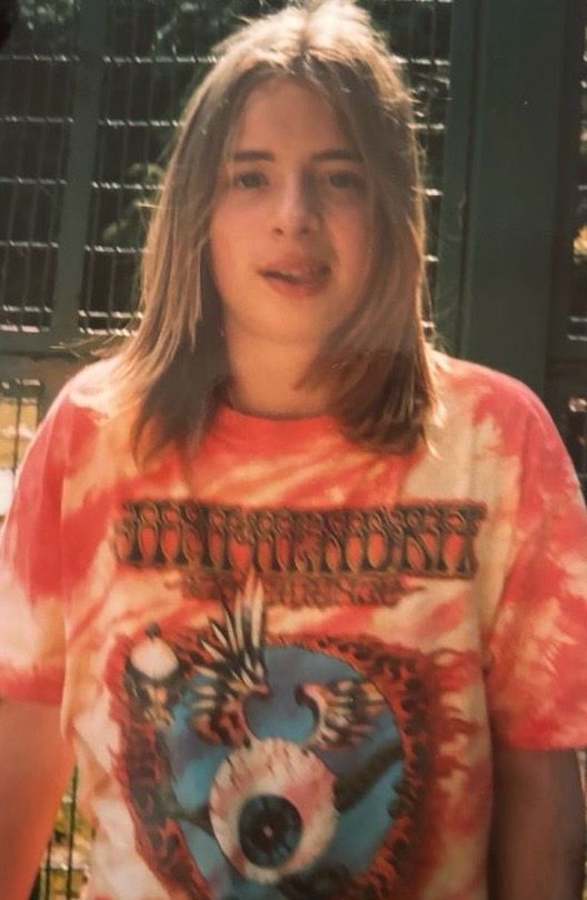 A young man with long hair wearing a tie-dyed Jimi Hendrix Experience t-shirt