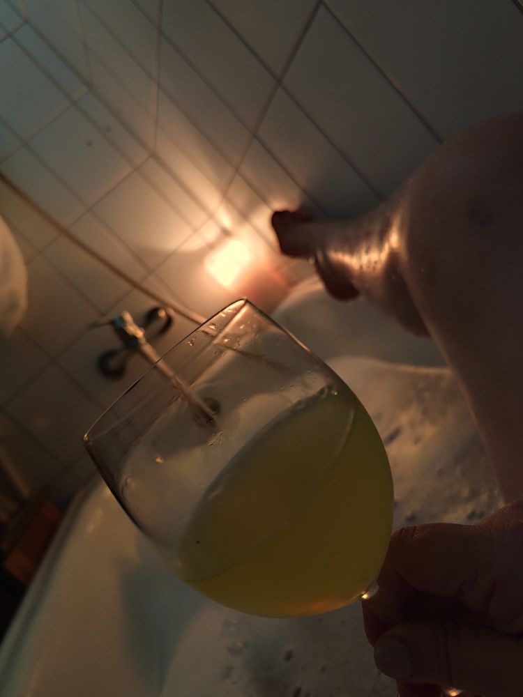 Die unseren liegt in der Badewanne im Halbdunkel. Ein Bein ist hochgelegt. In der Ecke brennt einen große Kerze. In der Hand hält sie einen hellen Cocktail.