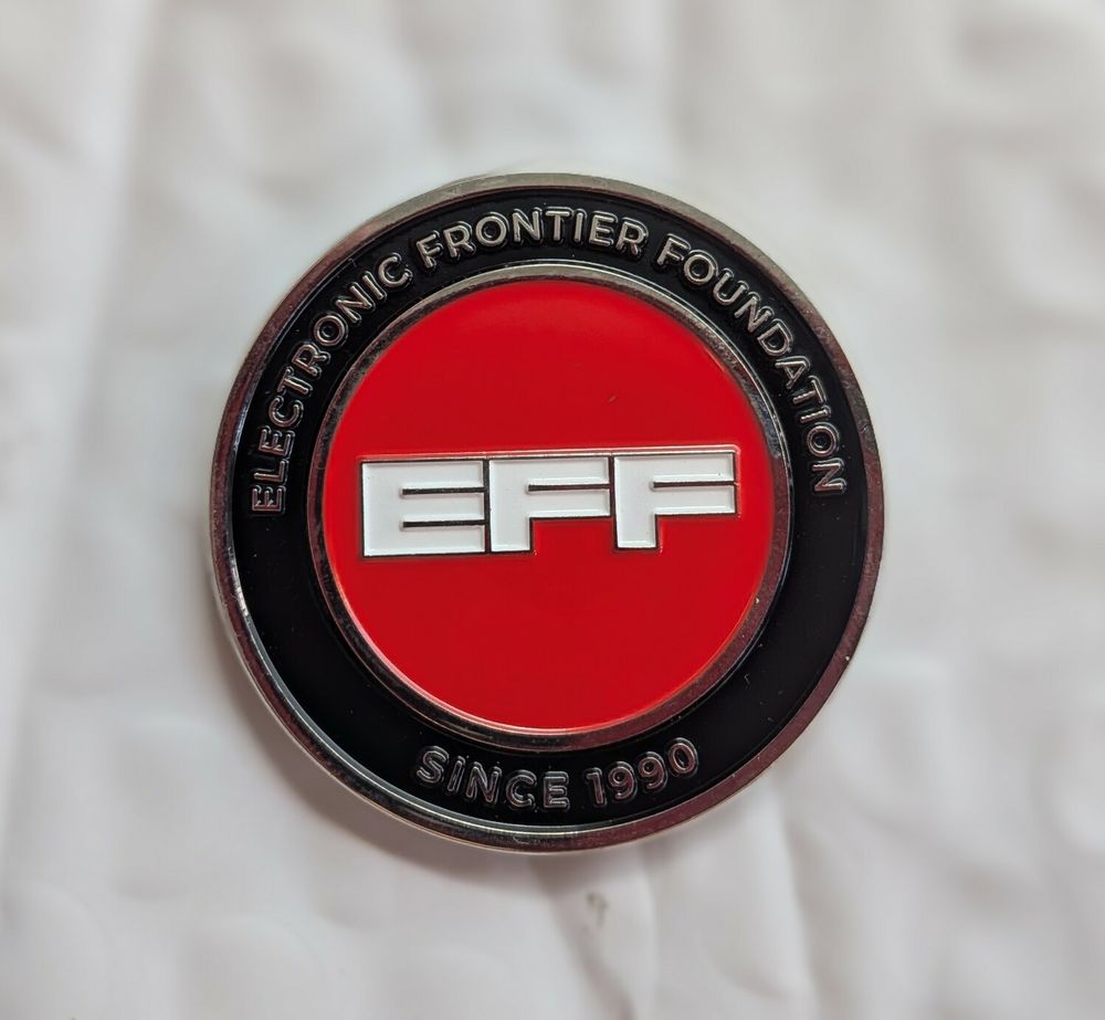 A photo of a small challenge coin, showing the EFF logo and the words "since 1990"