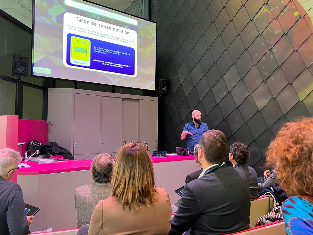 Christophe Le Roy, médiateur scientifique, présente l’animation au public présent.
Il est devant l’écran de présentation sur lequel on peut voir la définition du « talon de consommation » et une illustration de compteur Linky.