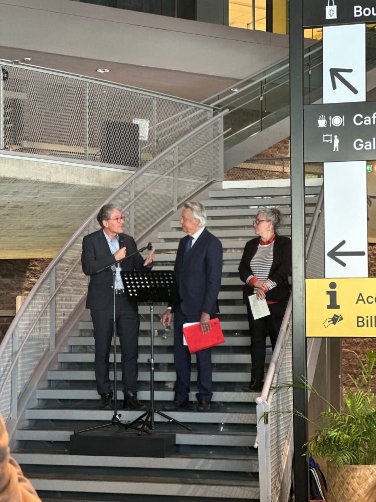 Michel Cabaret, François Saint Bris et Rozenn Andro dans un escalier devant un pupitre, pour le discours d'inauguration de l'exposition.

