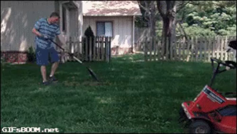 a man is raking a lawn in front of a golf cart