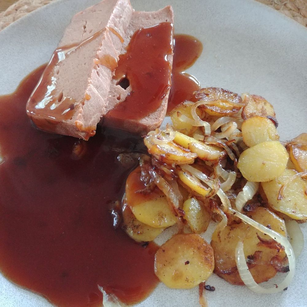 Ein Teller mit zwei Scheiben Leberkäse, Bratkartoffeln und Bratensoße
