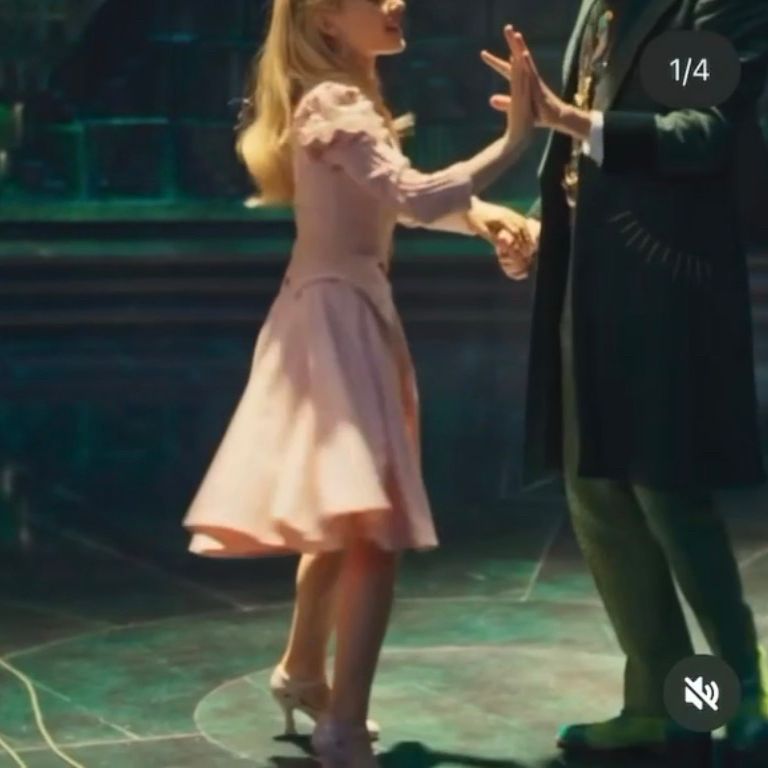 Photo from behind the scenes of Wicked of Ariana as Glinda and Jeff as The Wizard of Oz. The Wizard and Glinda have their hands closest to the camera pressed palm to palm and their pair of hands farthest from the camera clasped tightly. You can see a big smile on Ari’s face, but Jeff’s is cropped off at the top. 
