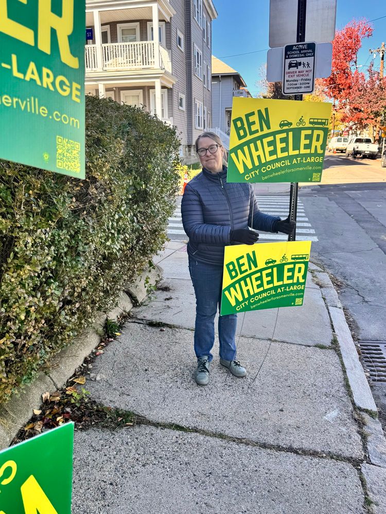 A woman holds a Ben Wheeler campaign sign