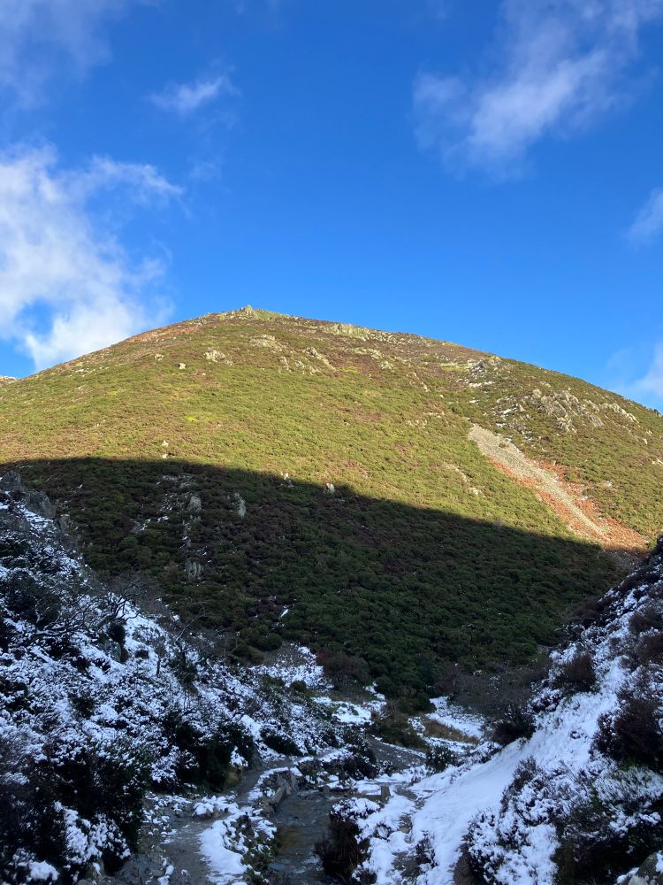 Sunlit hill in the distance with snowy, shaded land in front 