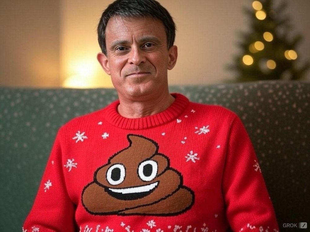Manuel Valls arborant un pull de Noël orné d'une grosse merde souriante 