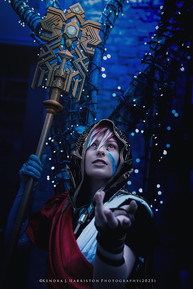 Hooded sorcerer with red & white hair, looking skywards, while holding on to his signature staff, whist holding out his hand. 
