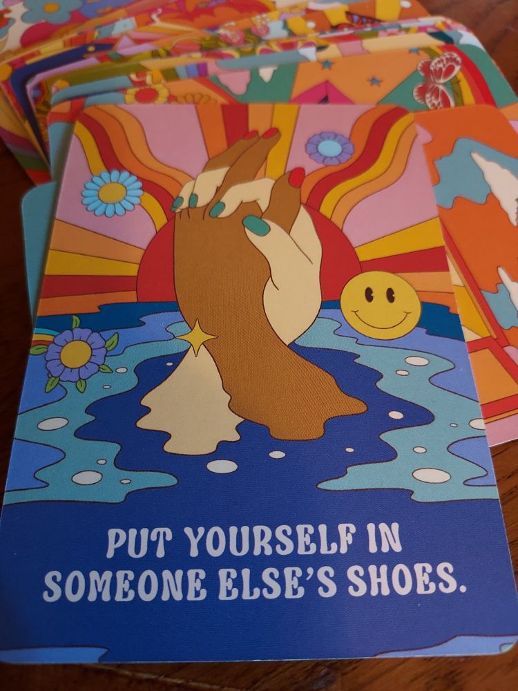 Cards for Daily Gratitude text and illustrations by Brooklyn Downing and Sheriece Robinson 2024 illustrated by Aleksandra Tolmacheva 
"Put yourself in someone else's shoes."
Picture shows a colorful sun rising behind two hands clasped together that are coming up out of the water.