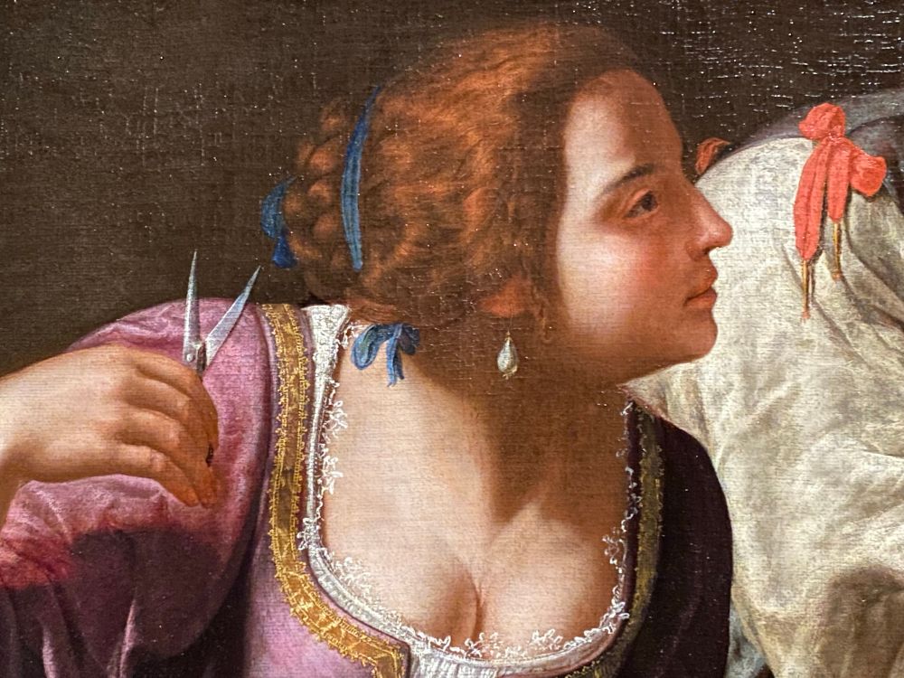 Delilah is shown in profile, holding scissors in her right hand 