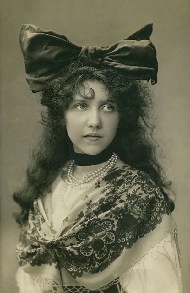 A photograph of woman from the early twentieth century with an enormous bow on her head