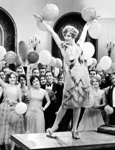 Joan Crawford strikes a triumphant pose on a table.