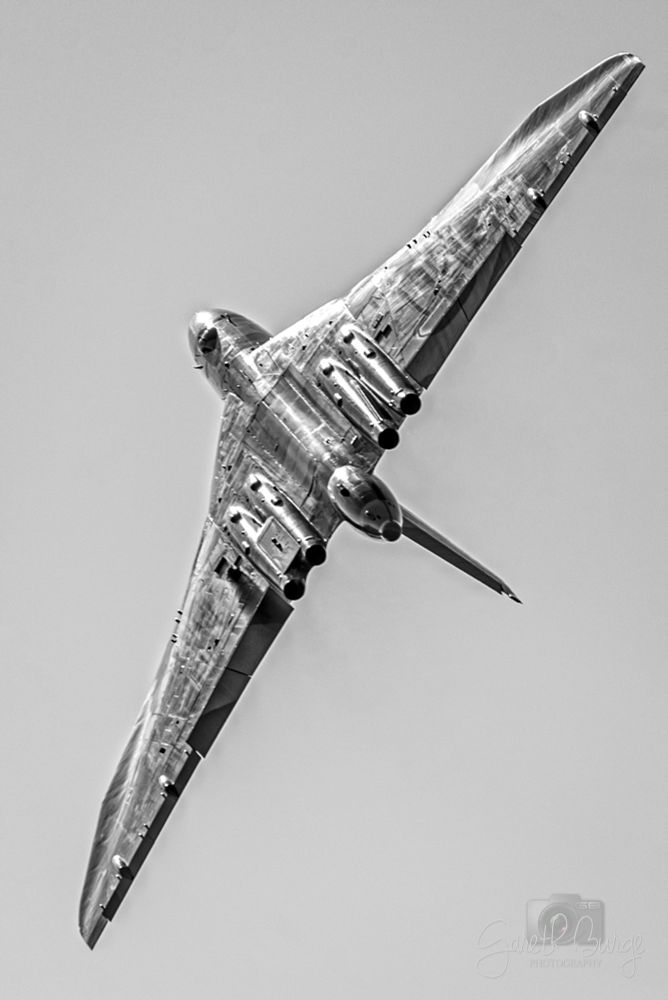 Mono photo of the underside of a Vulcan bomber banking away from the camera. Underside detail is very visible in the sunlight