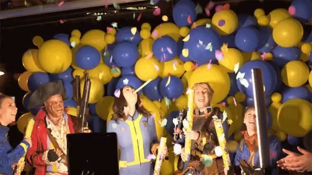 a group of people are standing in front of a wall of balloons and confetti