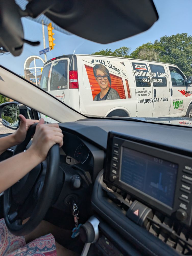 A picture of a woman with glasses and an asymmetrical haircut that looks a bit gay emblazoned on the side of a UHaul 