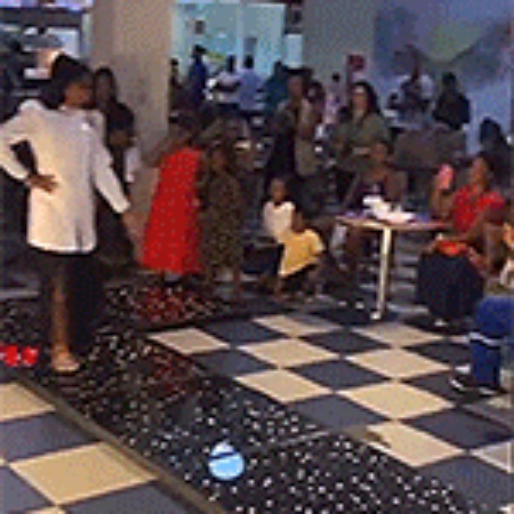 a group of people are gathered around a checkered floor .