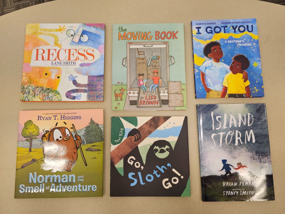 Six books on a table from top left: Recess by Lane Smith, The Moving Book by Lisa Brown, I Got You by Derrick Barnes with Shamar Knight-Justice, Norman and the Smell of Adventure by Ryan T. Higgins, Go Sloth Go by Toni Yuly, and Island Storm by Brian Floca with Sydney Smith. 
Not pictured include Earl & Worm The Big Mess by Greg Pizzoli and Go Baby Go by Tara Dairman with Olivia Amoah.