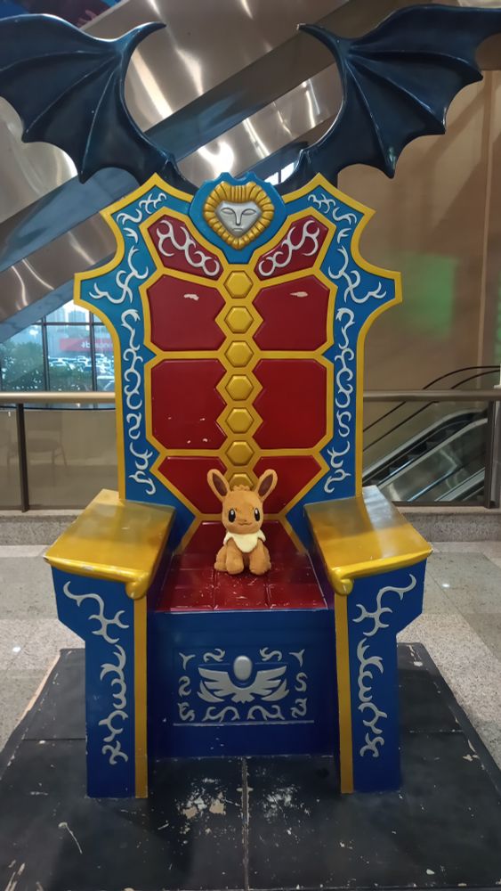 An Eevee plushie sitting on Hades' throne from Saint Seiya