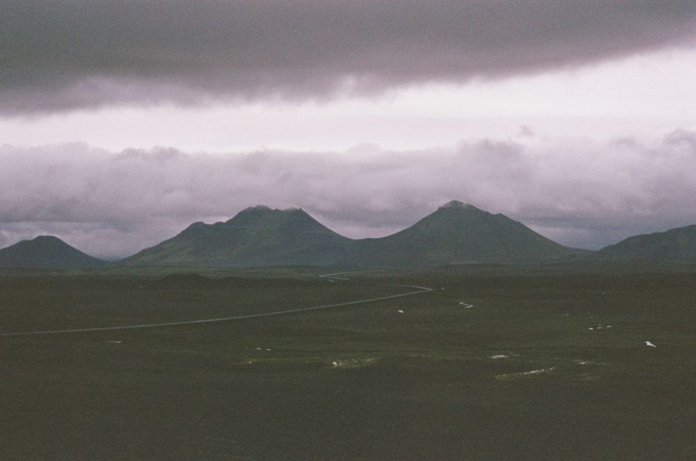 Mountains in the distance cut the photo in half, separating the rocky landscape from the grey, cloudy sky.