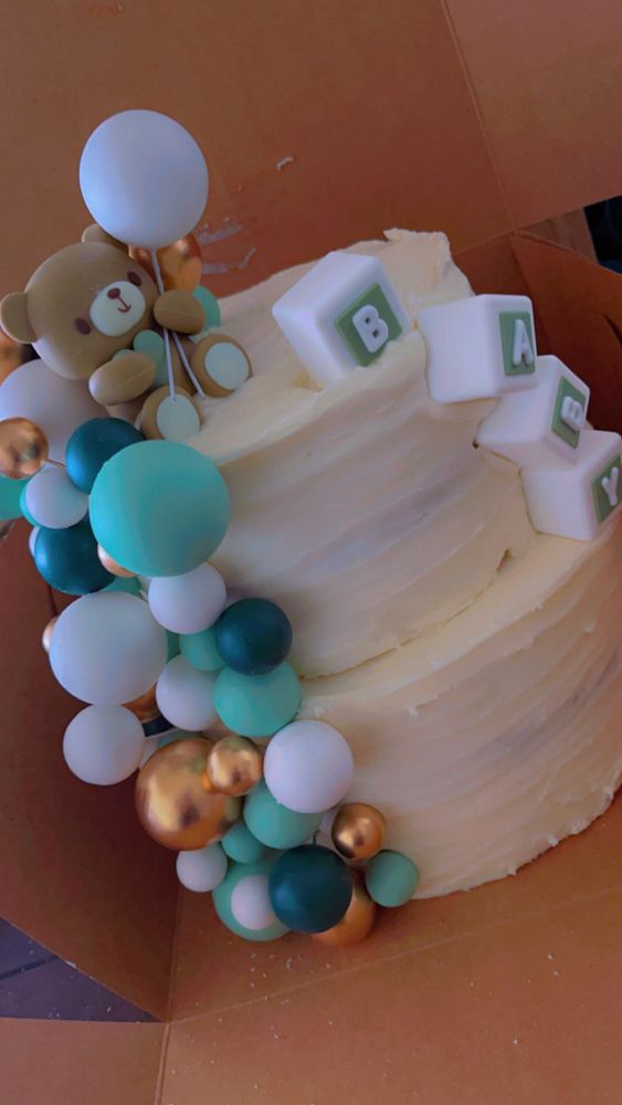 Two tiered white cake with green, white & gold decorations.