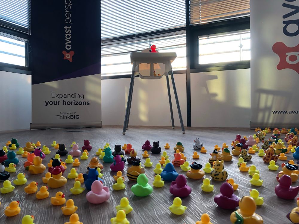 Devil in form of rubber duck standing on hightened platform being worshipped by a crowd of smaller ducks. View from angle of his worshippers.