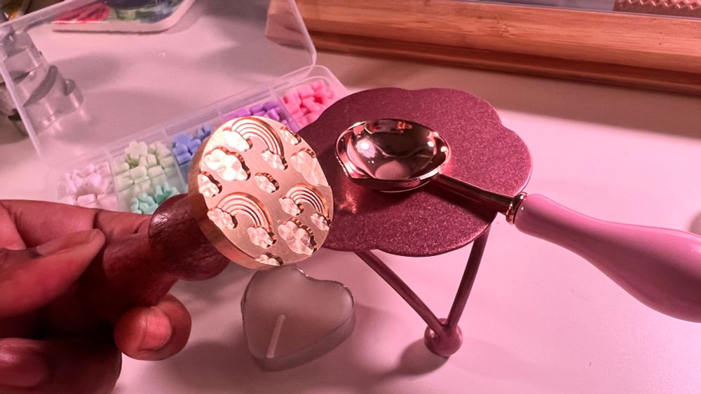 a picture of a wax sealing spoon, furnace, some sakura-shaped wax beads, and a head shaped candle wrapped in tin
