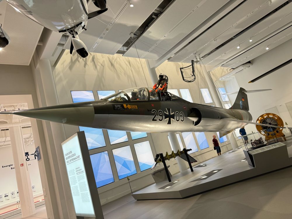 German Air Force (Luftwaffe) twin-seat Lockheed F-104 Starfighter suspended from a museum ceiling, with the rear crew member displayed as ejecting from the aircraft.