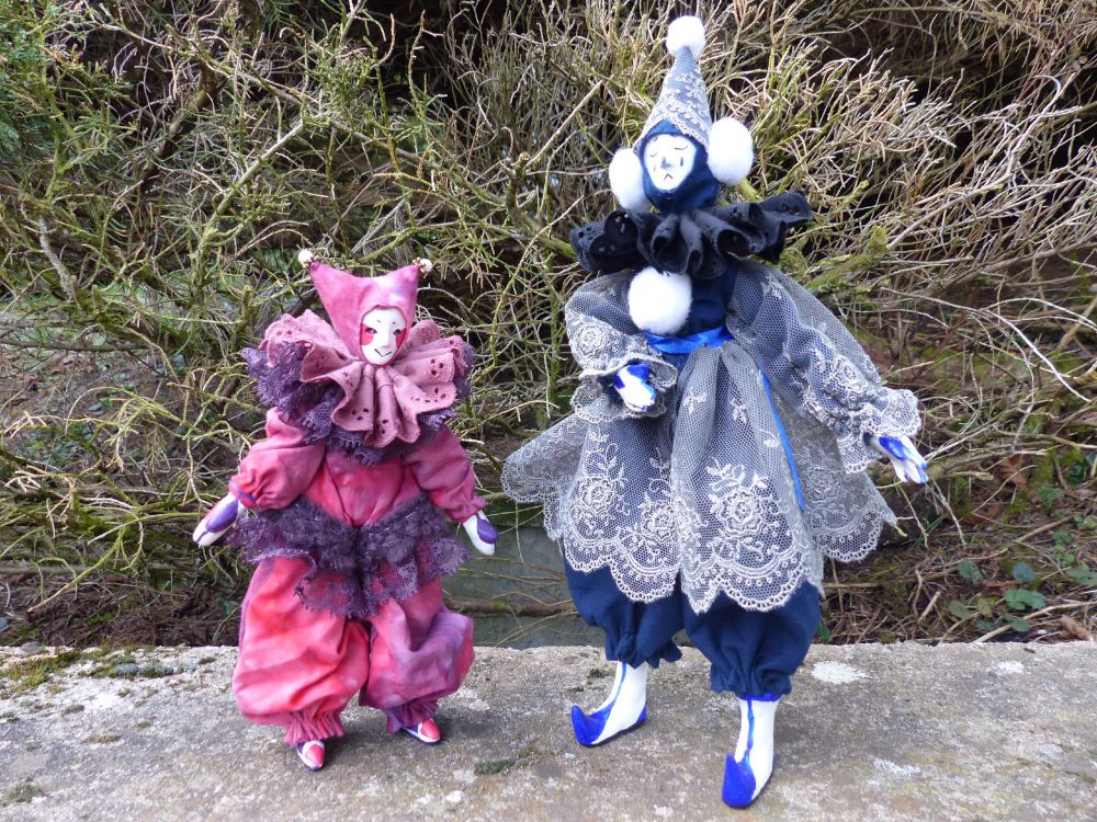 photo of 2 OOAK dolls. The one on the left is a pink jester wearing a twop point hat, it's smaller to the one on the right who is dressed in blue and greys, with only one point on its hat, it looks more like a pierrot