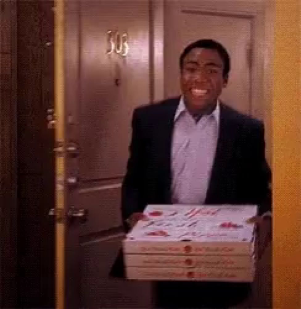 a man in a suit is carrying three boxes of pizza into a doorway .