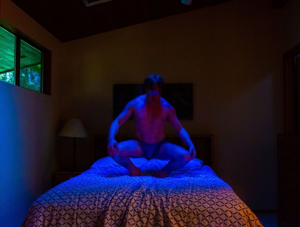 possession, blue figure on bed lit darkly with red, muscled forward