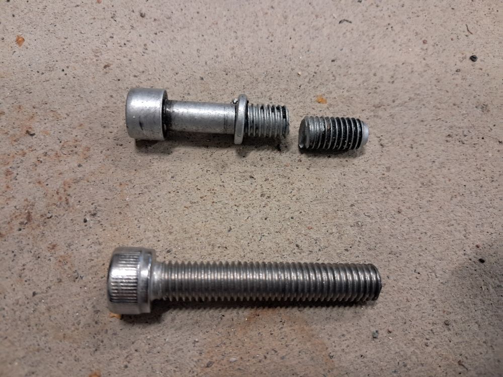 Photograph depicting a crappy cheap bolt of some unknown alloy that almost got a beautiful lesbian killed when it snapped in half when she was cycling down a hill, and the flawless replacement she cut from a 15cm long stainless steel bolt that will at least get her home tonight