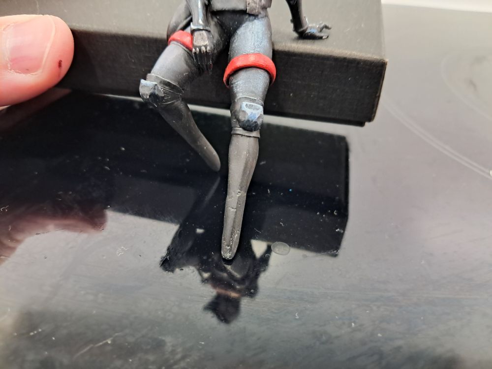 Photograph depicting a kitbashed "75mm" Elster miniature from Signalis. It's been extremely heavily customised from an entirely different mini to look as much like her as possible.
Specifically the legs and chest plate in these images were modelled from milliputt, and had serious problems with rough surfaces and irregular shapes on account of me doing it entirely with my fingers and without vaseline to prevent fingerprinting and adhesion to my fingers. They have now been sanded down with fine-grit sandpaper, cleaned and repainted to provide a much better finish. Details can now be painted on top to show the ties etc.